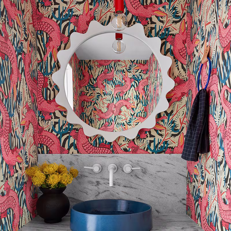 Whimsical alligator wallpaper in a bathroom with a blue sink