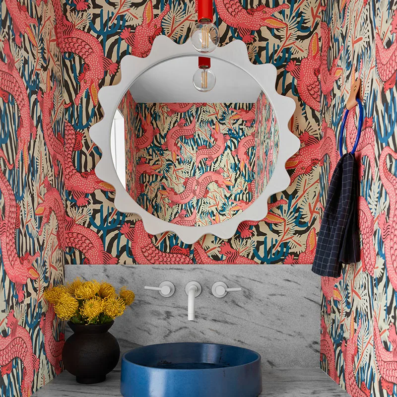 Whimsical alligator wallpaper in a bathroom with a blue sink