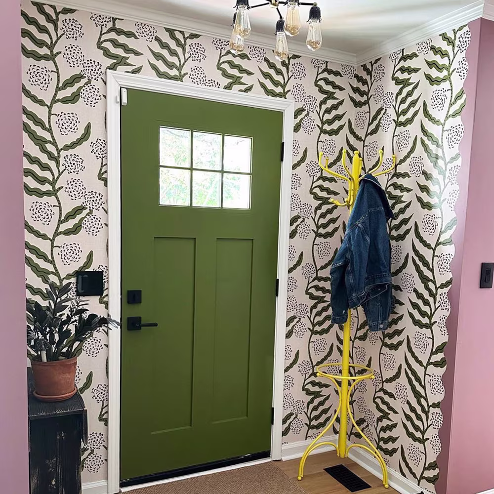 Entryway with green door and green vining wallpaper.