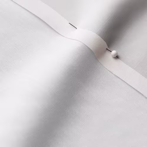 A close-up photo of white fabric with a pin running through it