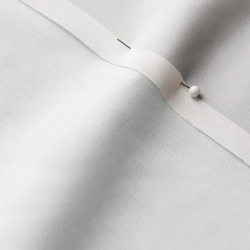 A close-up photo of white fabric with a pin running through it