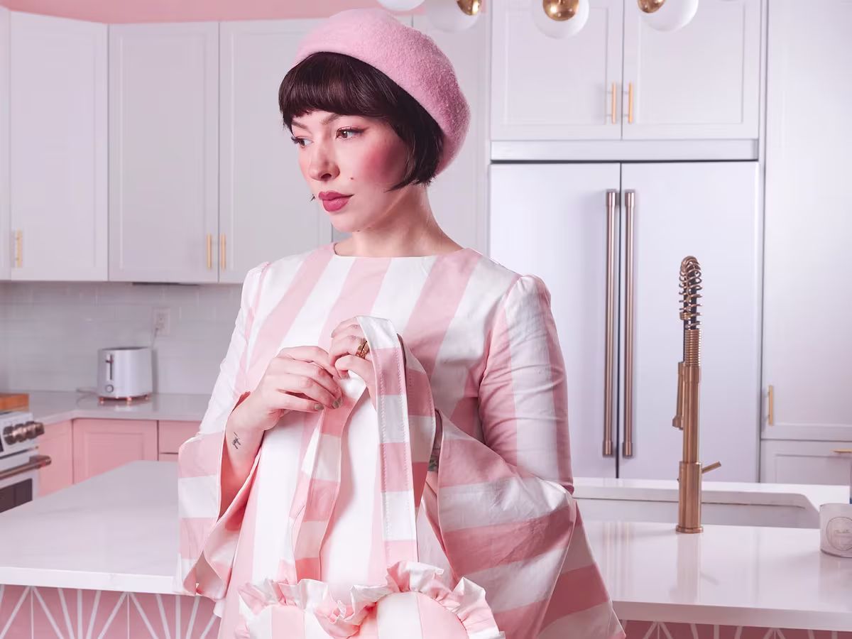 Keiko Lynn wearing a pink and white striped dress with matching ruffled bag made with cotton poplin