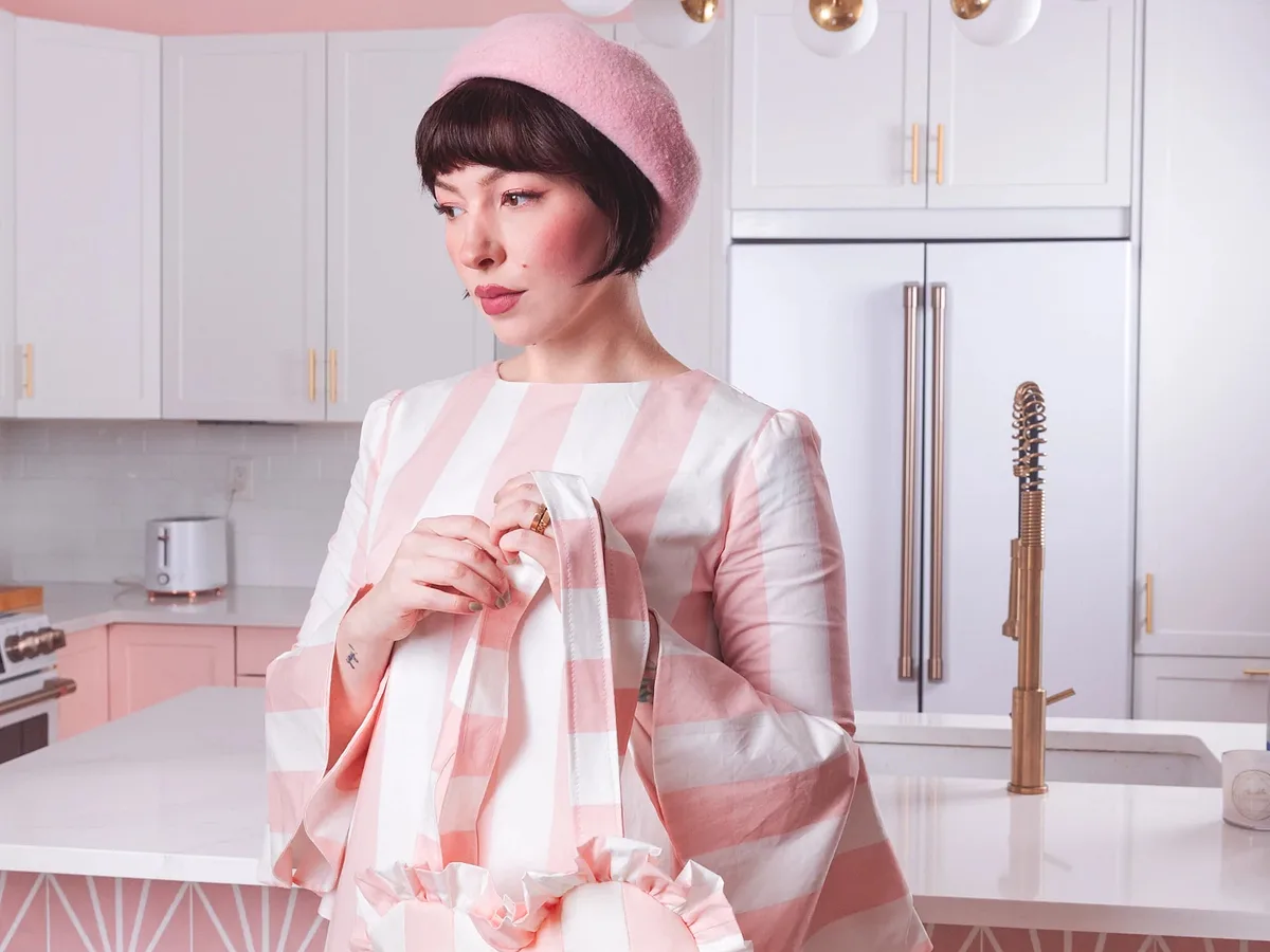 Keiko Lynn wearing a pink and white striped dress with matching ruffled bag made with cotton poplin
