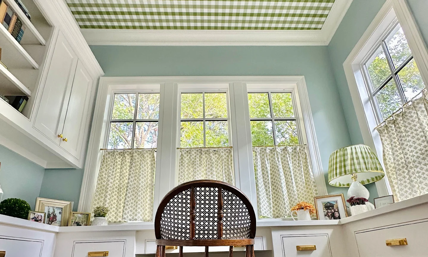 Home office space with block printed cafe curtains and coordinating gingham lampshade, chair cushion and ceiling wallpaper.
