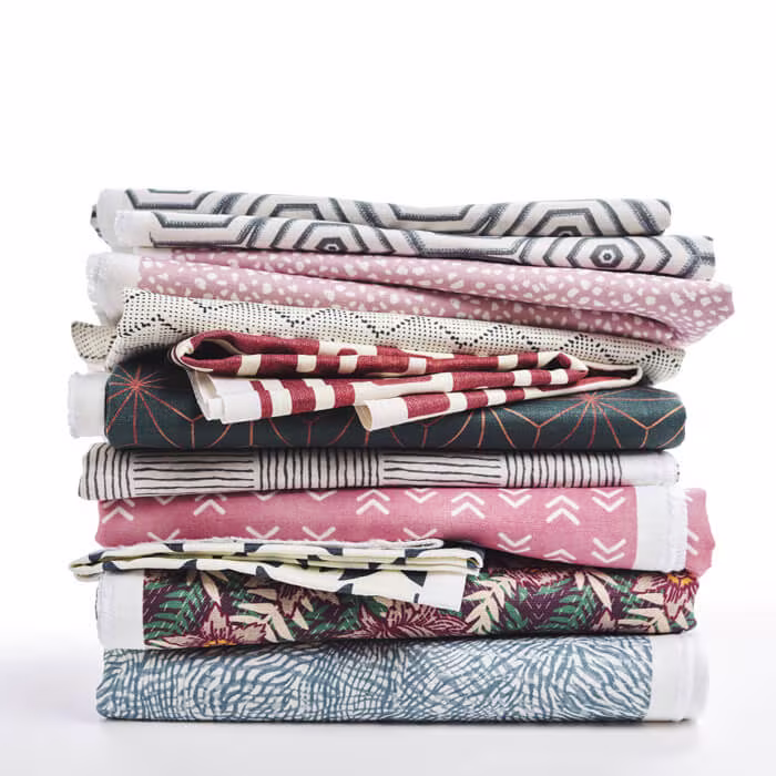 Close-up view of layered linen fabric featuring a soft watercolor-style floral print in pink, peach, and green tones.