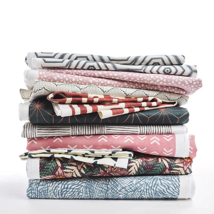 Close-up view of layered linen fabric featuring a soft watercolor-style floral print in pink, peach, and green tones.