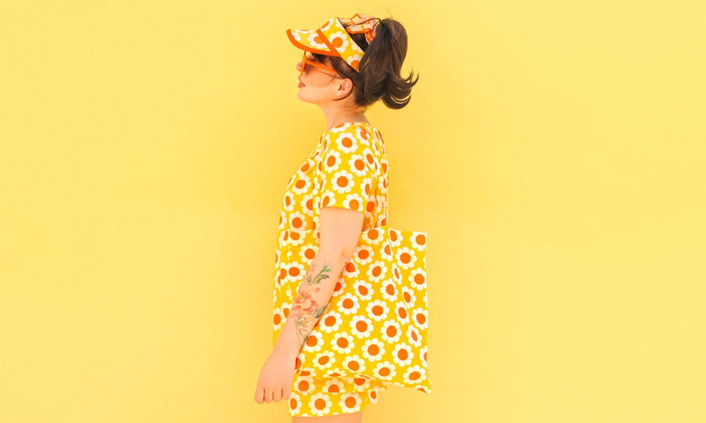 Keiko lynn in a yellow floral outfit against a yellow wall.