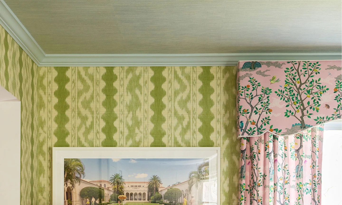 Dining room with green striped wallpaper on the walls blue grasscloth wallpaper on the ceiling and pink curtains with a tree pattern.