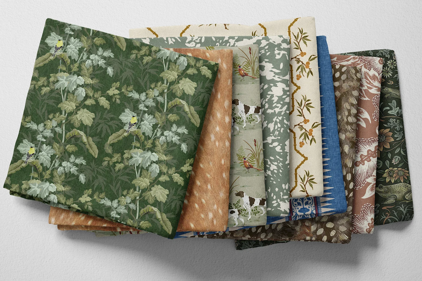 Colorful folded Spoonflower fabric with a selection of classic country heritage prints in green, cream, blue, and brown