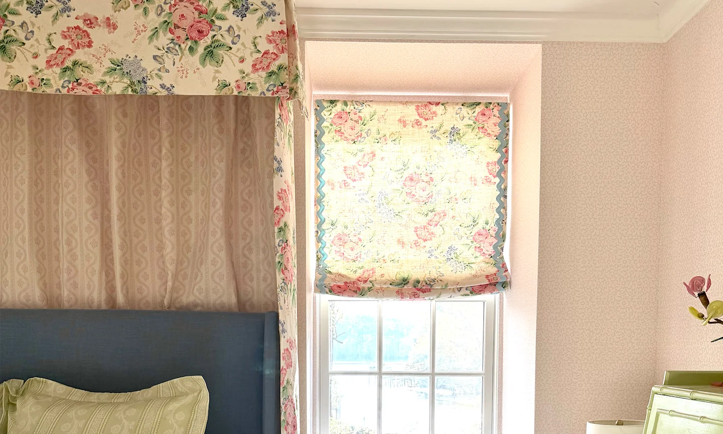 Girls bedroom with pink wallpaper chintz floral roman shades and matching canopy over a bed.