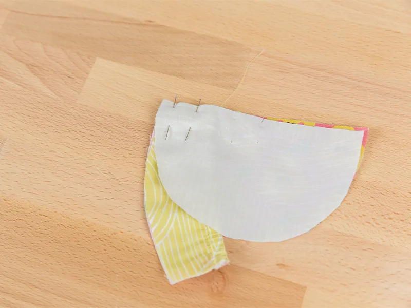 Materials to make the baby shoe's toe are pinned together.