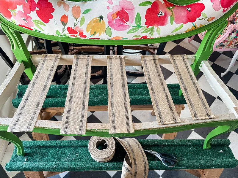 Strips of jute webbing stapled vertically across the settee seat's frame.