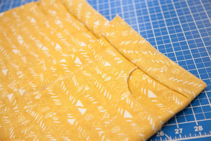 A close up of the yellow skirt, design side out to show the waistband and seam allowance have been pressed up, away from the skirt.