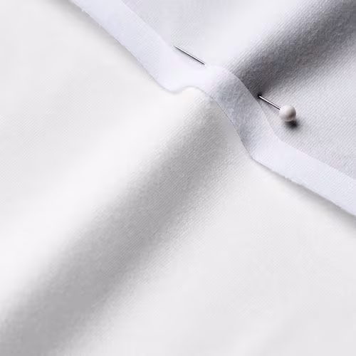 A close-up photo of white fabric with a pin running through it