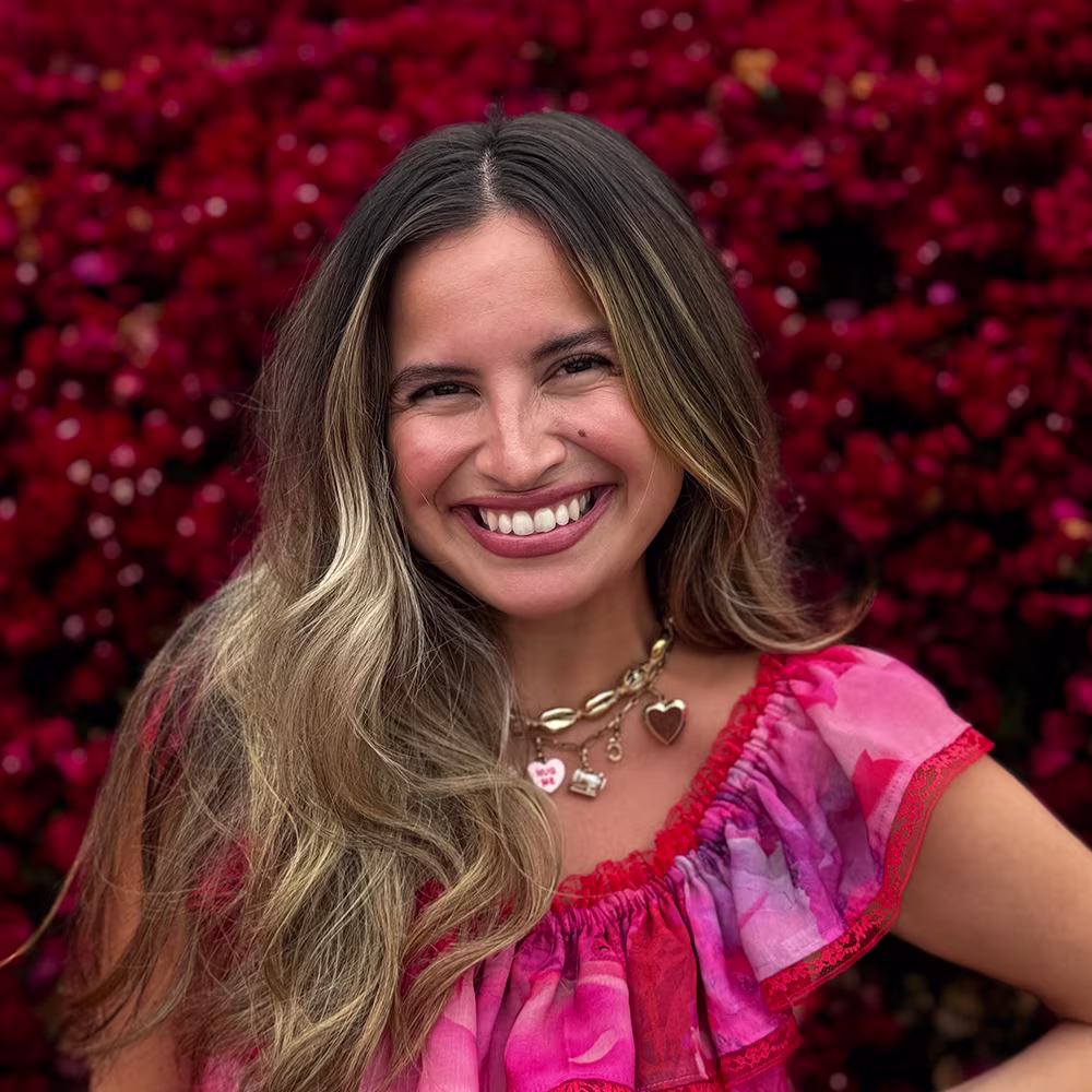 A headshot of Alissah Threads in her handmade vibrant pink and red dress