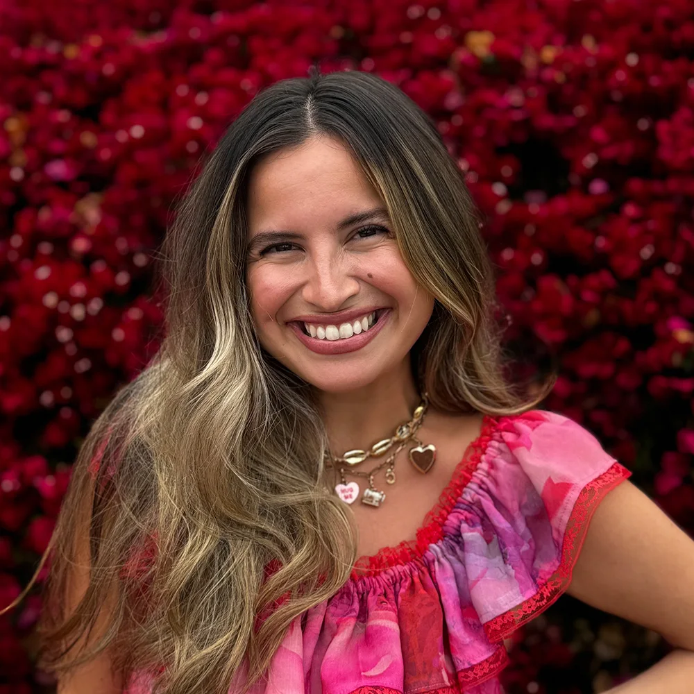 A headshot of Alissah Threads in her handmade vibrant pink and red dress