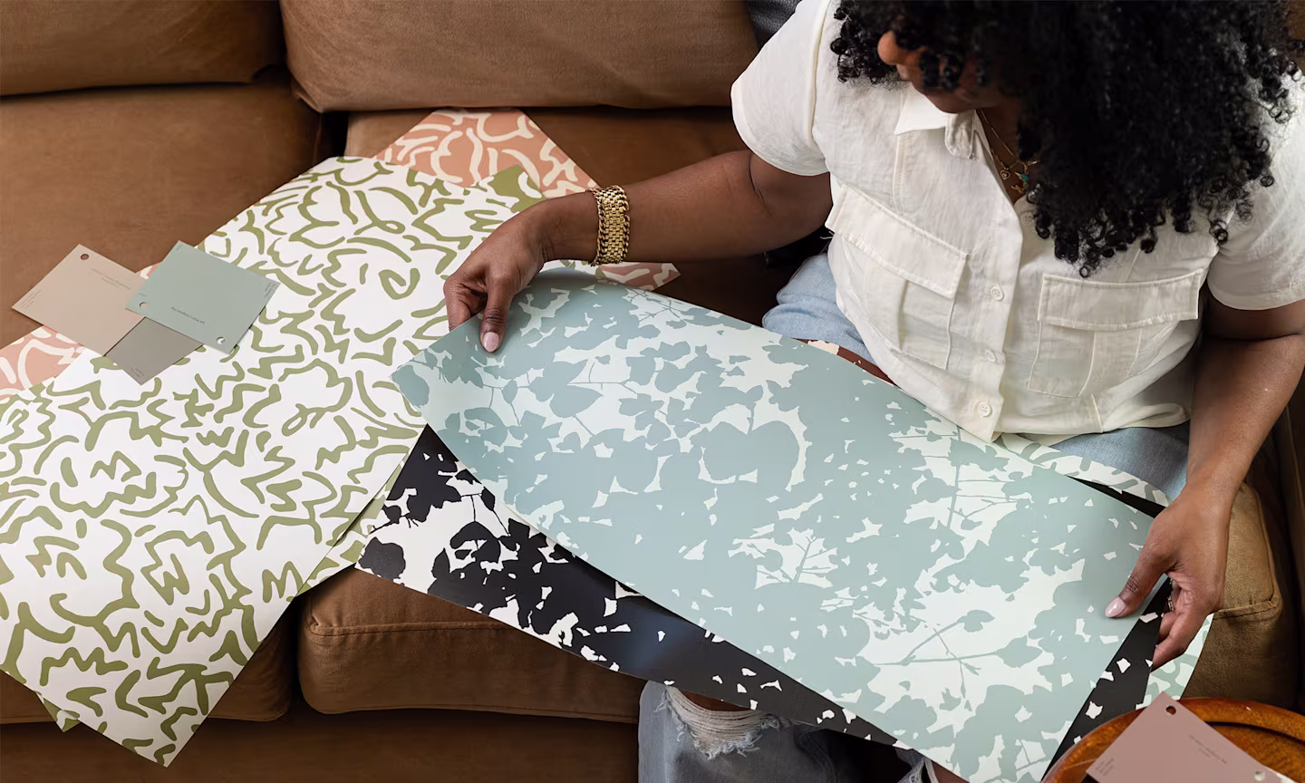 Marie holding swatches of her wallpaper designs from the INNER CALM capsule.