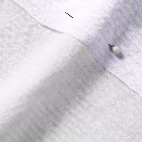 A close-up photo of white fabric with a pin running through it