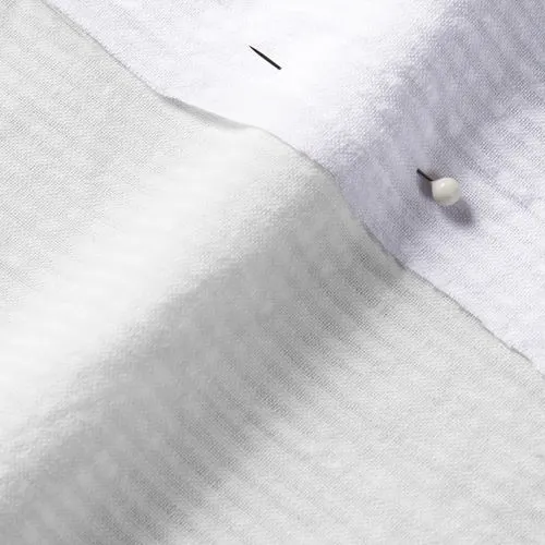 A close-up photo of white fabric with a pin running through it