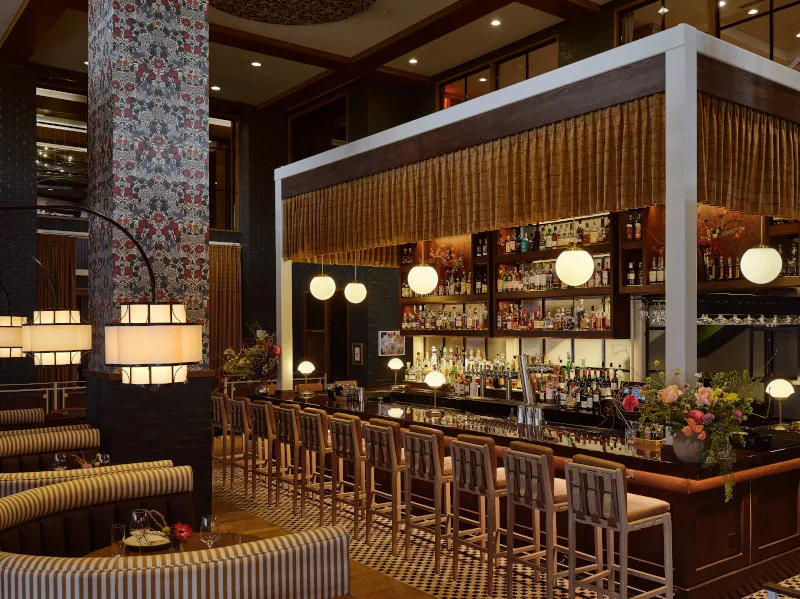 Bar image with booths and a column with floral wallpaper.