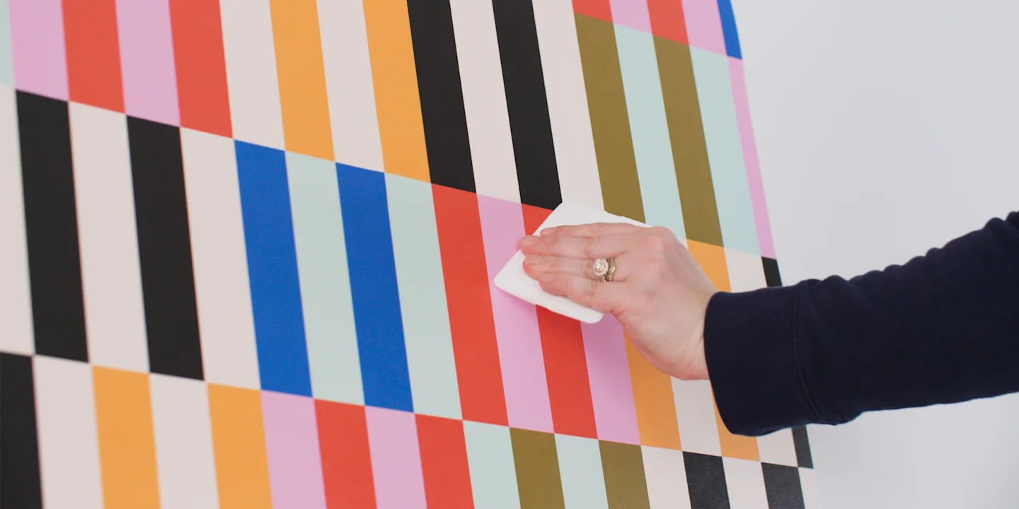 Person smoothing out peel and stick wallpaper.