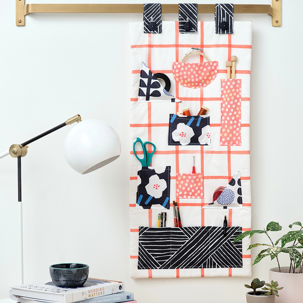 Fabric tool/craft supplies organizer hanging above a workspace.