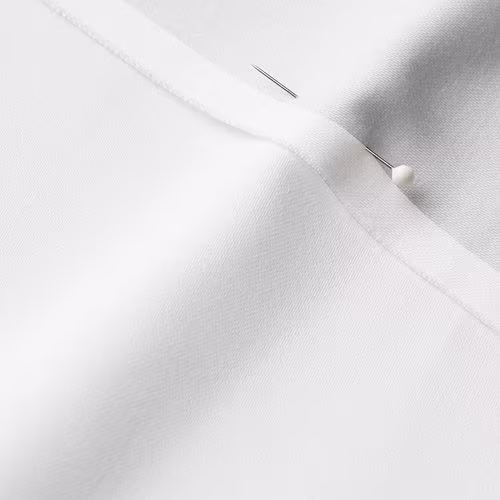 A close-up photo of white fabric with a pin running through it