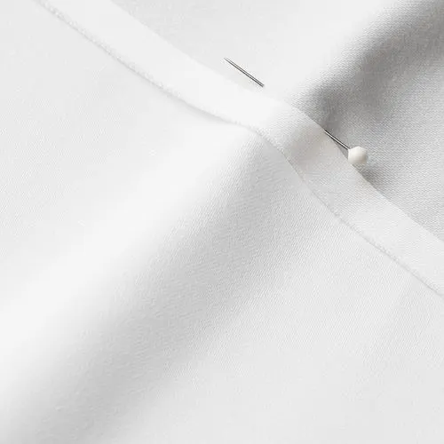 A close-up photo of white fabric with a pin running through it