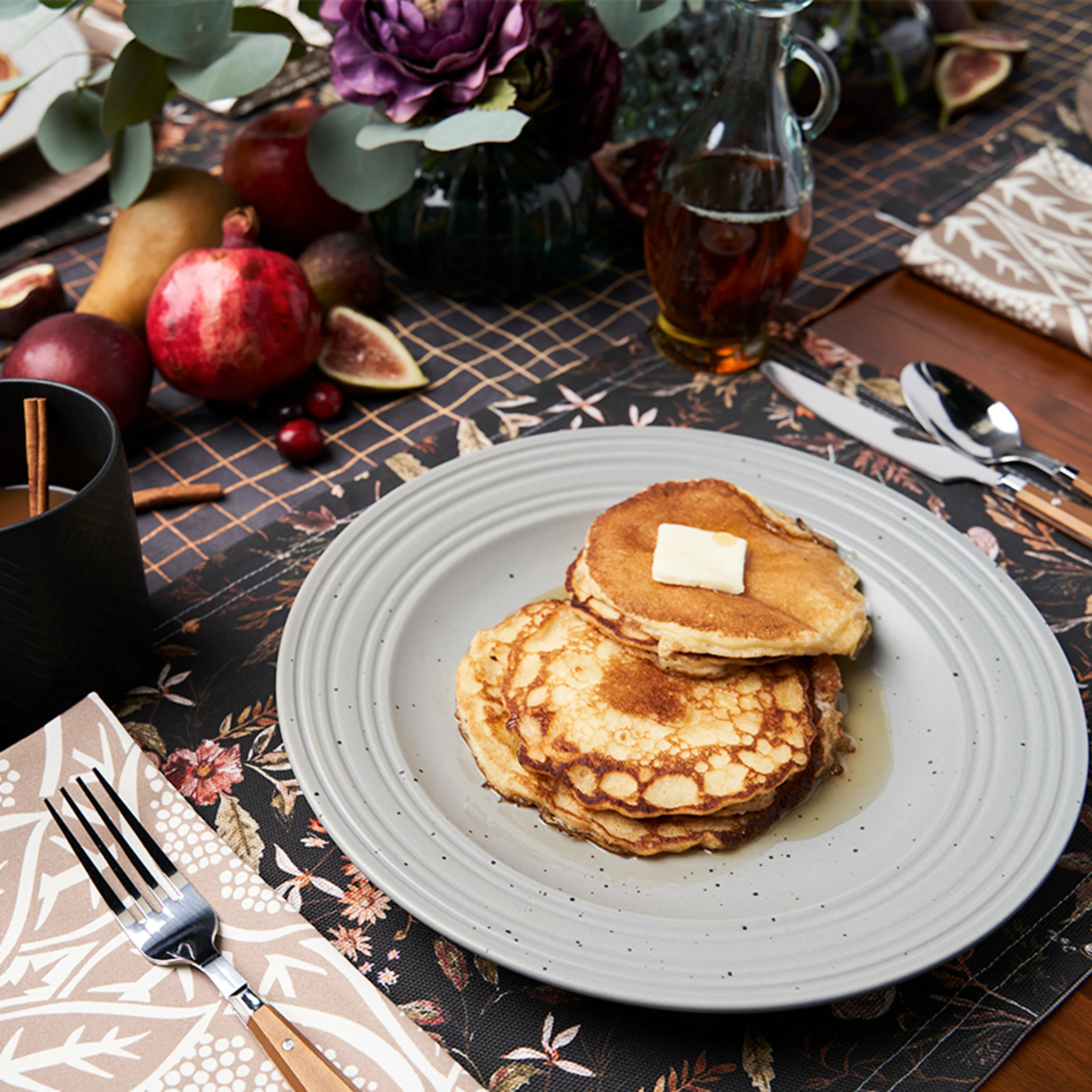 Dining table set with dark floral and pomegranate linens
