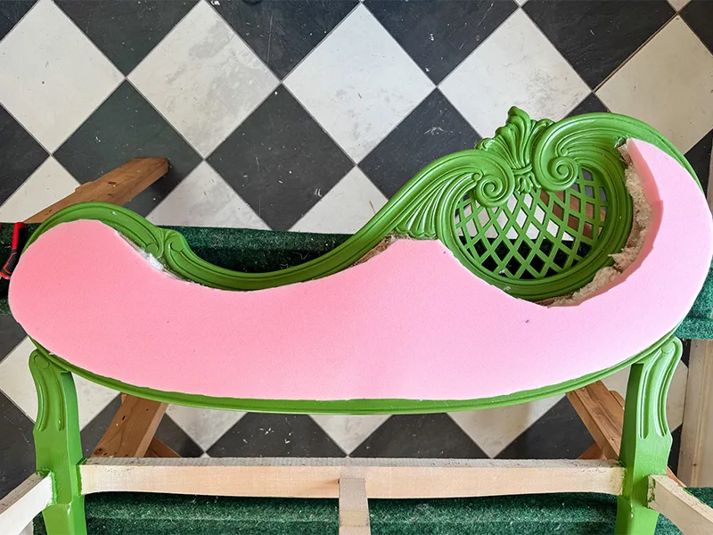 A foam cutout on the settee top that lays on a sawhorse. A checkered floor is in the background.