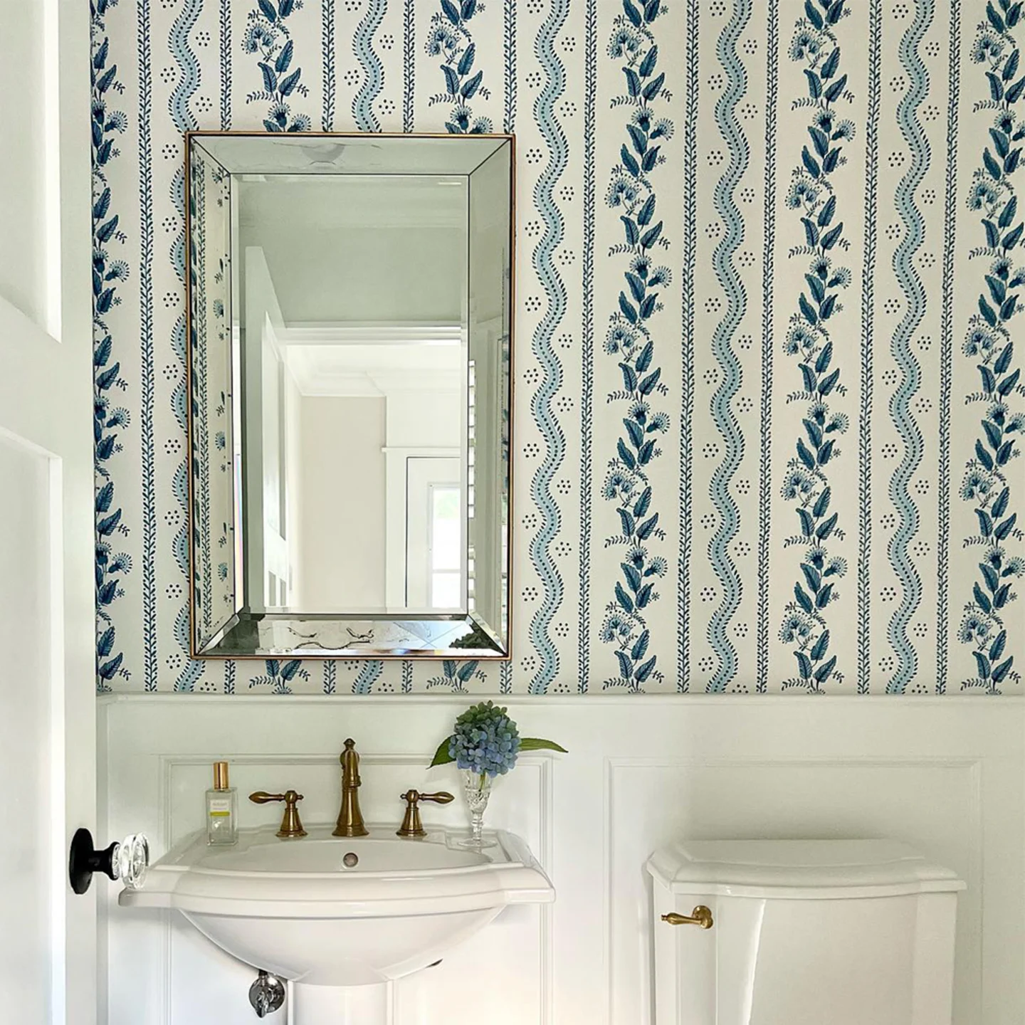 Powder room with blue floral striped wallpaper.