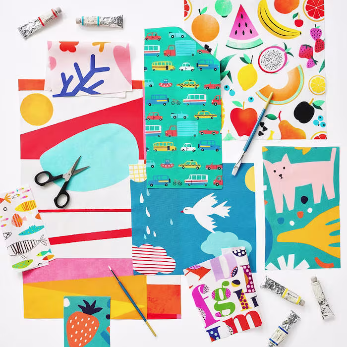 A flat lay of colorful fabric swatches with bold, playful designs, including fruit, animals, abstract shapes, vehicles, and graphic patterns.