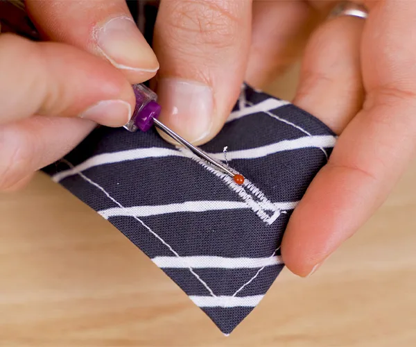Creating a buttonhole at the top of one of the craft organizer straps.