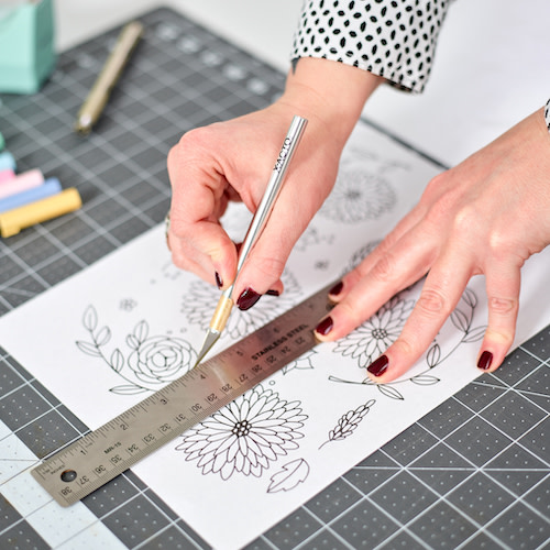 Hands measuring and cutting a design