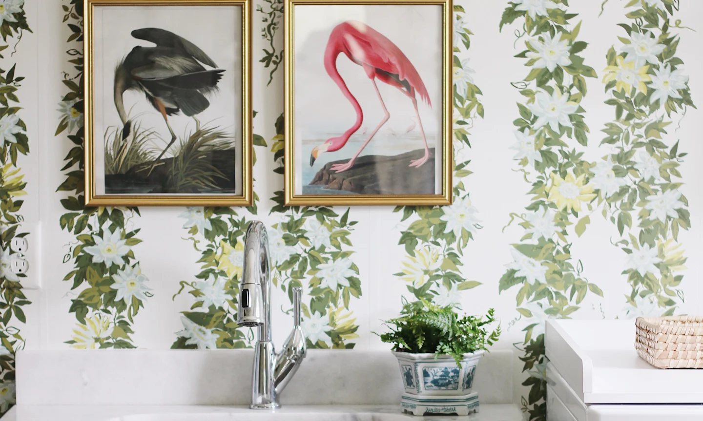 Laundry room with leafy, floral stripe wallpaper and art prints of birds.