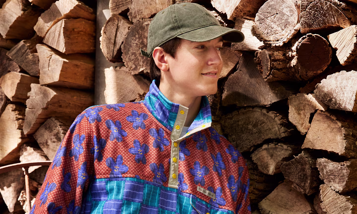 A model wearing a Polartec Fleece pullover leaning against a wood wall