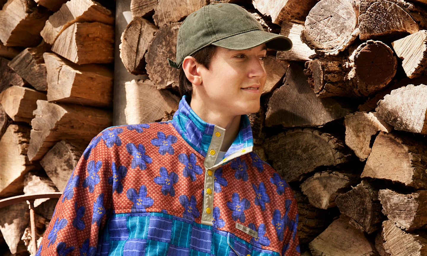 A model wearing a Polartec Fleece pullover leaning against a wood wall