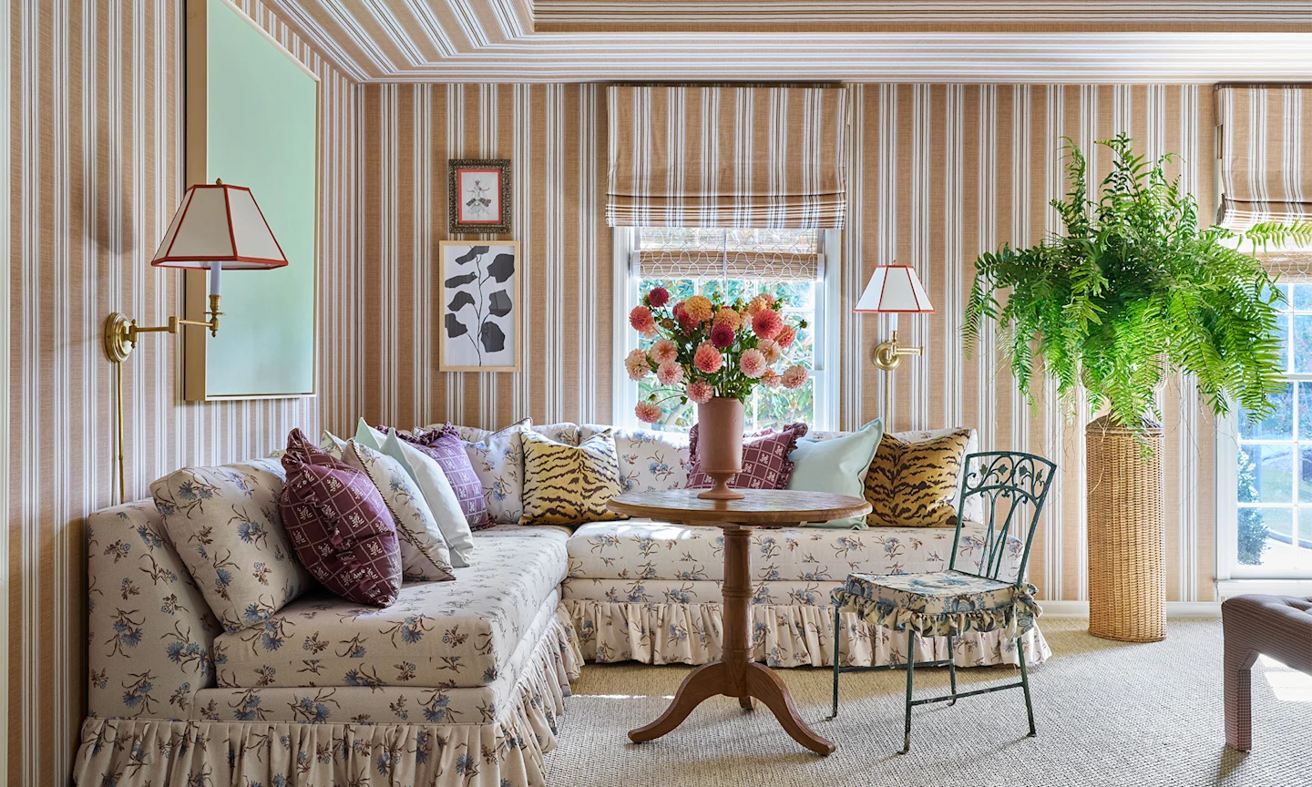 Living area with striped wallpaper on the walls and a couch upholstered in floral fabric.