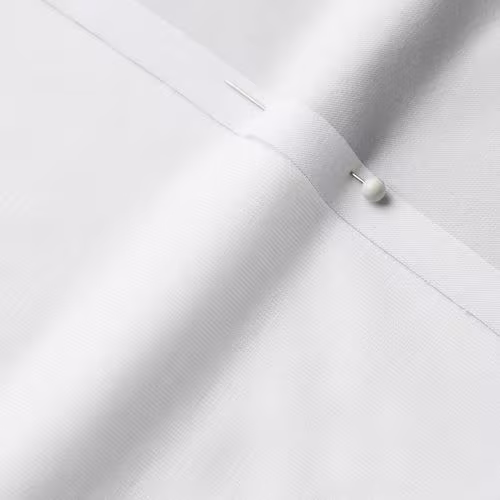 A close-up photo of white fabric with a pin running through it