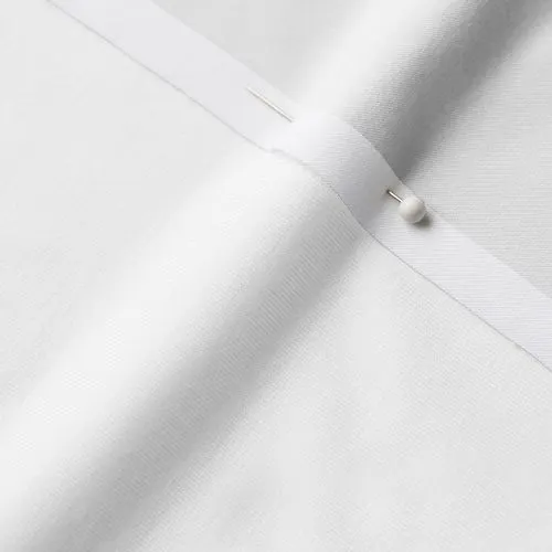 A close-up photo of white fabric with a pin running through it