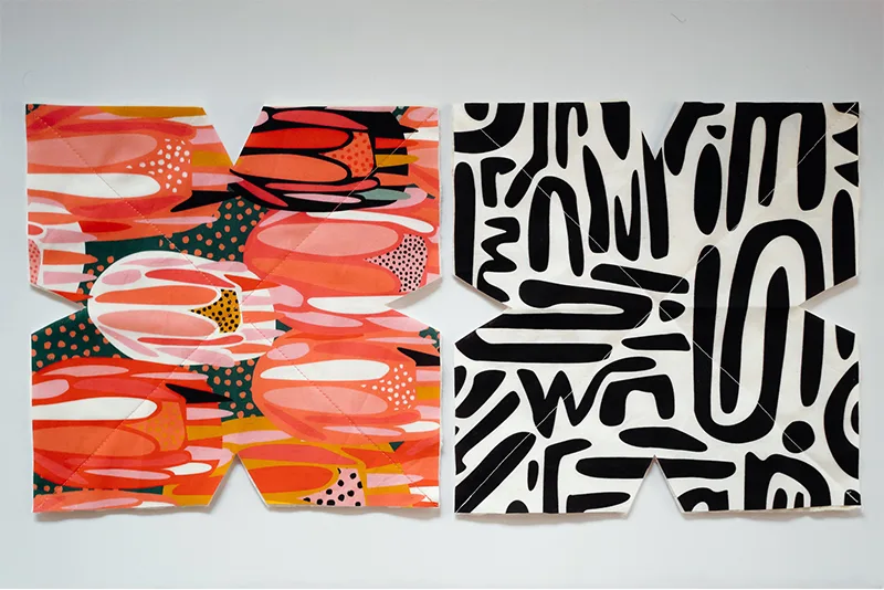 Two cut-out bowl cozy pattern pieces with the excess batting trimmed away. The fabric to the left features bright flowers in pinks, reds, yellows and white. The fabric to the right features black geometric lines on a white background.