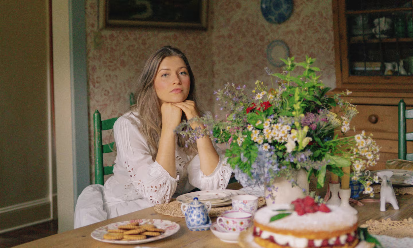 Headshot of Margo Roth at her dining room table that is filled with china, baked goods and flowers.