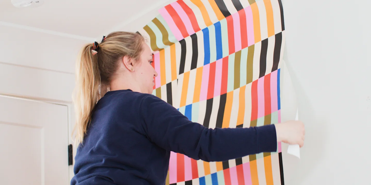 Person installing Peel and Stick wallpaper.