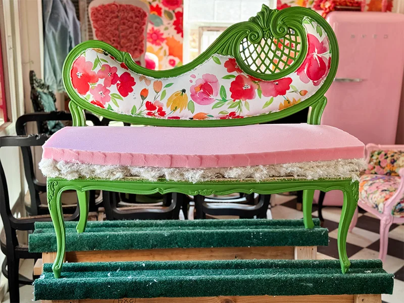 A piece of pink foam rests on top of the cotton layer on the settee's seating space.