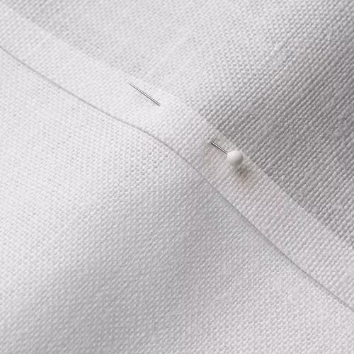 A close-up photo of white fabric with a pin running through it