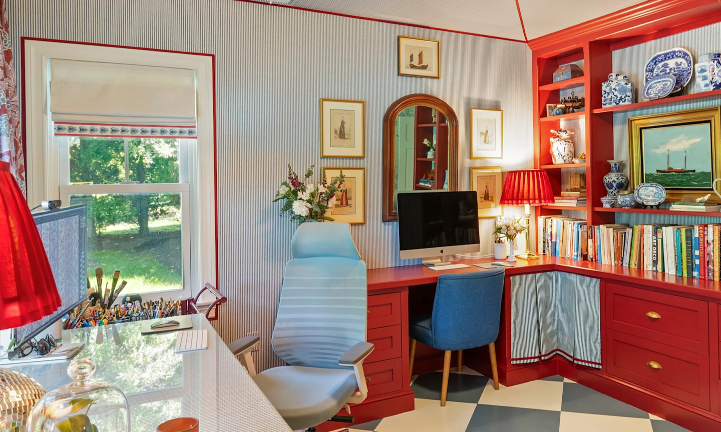 Home office space with blue pinstripe wallpaper and red shelving.