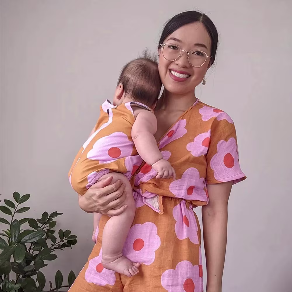 Woman in floral matching set holding baby wearing a onesie with the same pattern.