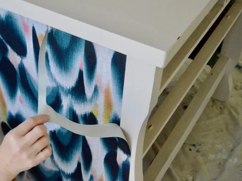 Barb removes the excess wallpaper that she's cut with her craft knife.