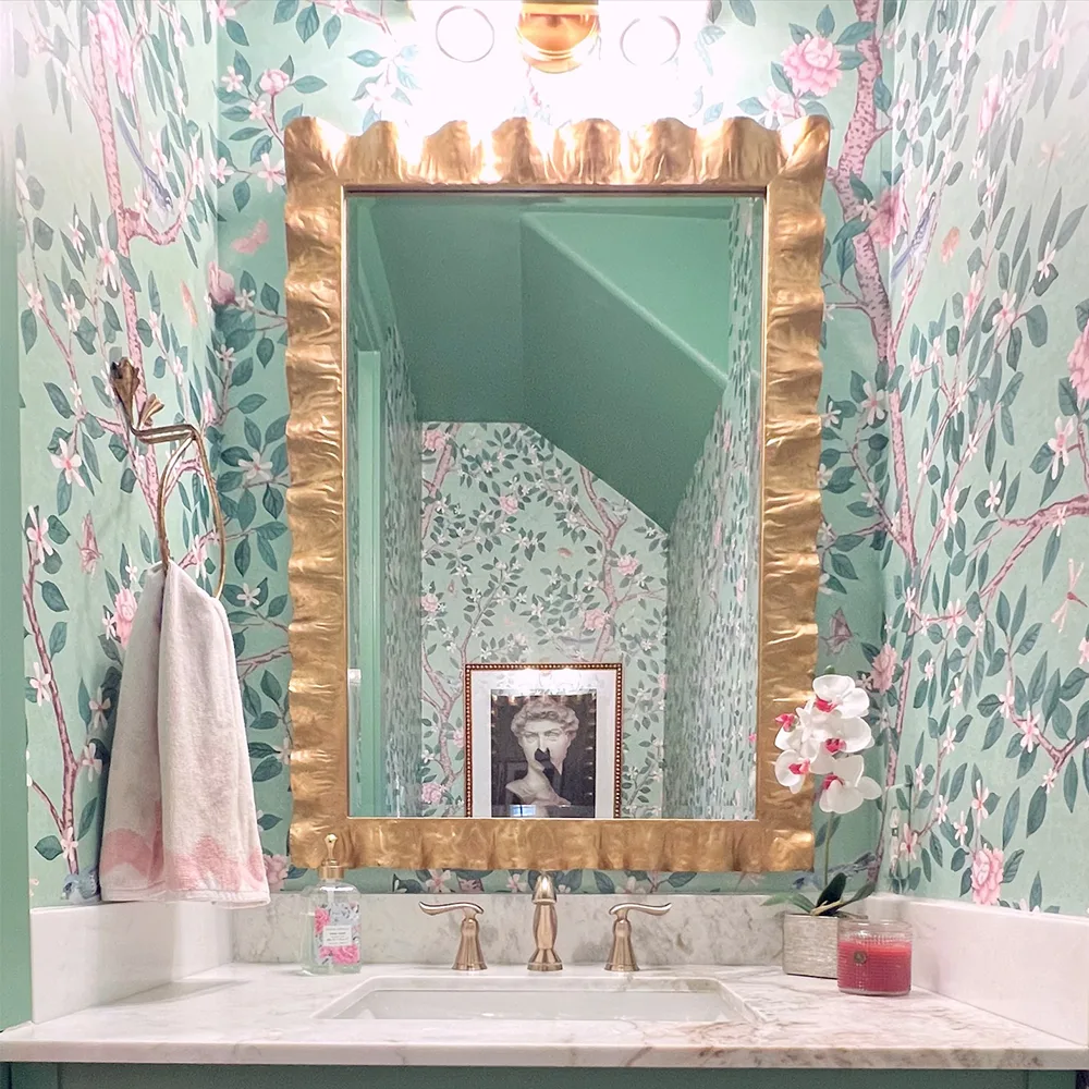 Bathroom with green branch and floral wallpaper.