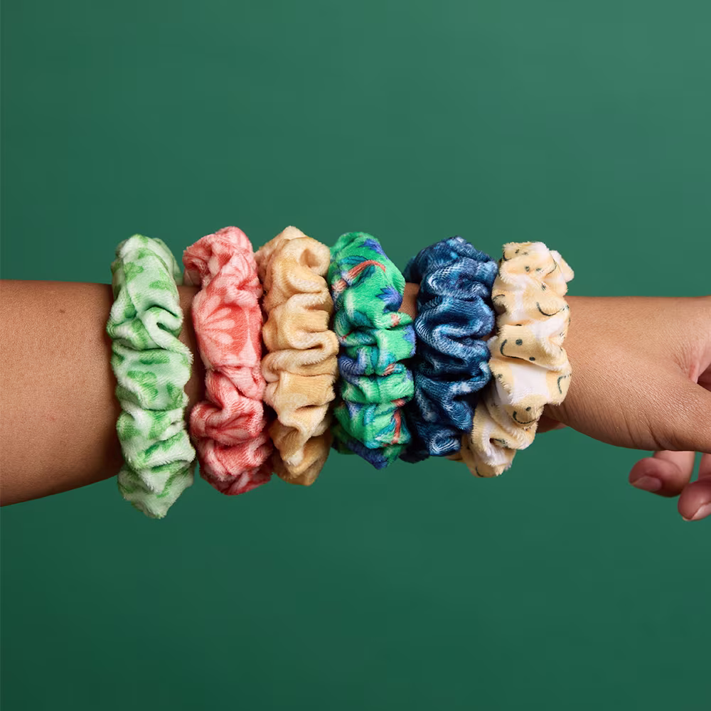 Back of girls head with hair pulled back by multiple colorful scrunchies.